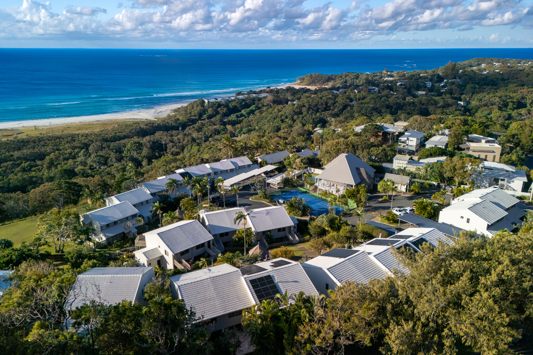 Pandanus Palms Resort from the air, the villas stepping down the headland with the beach and Coral Sea beyond