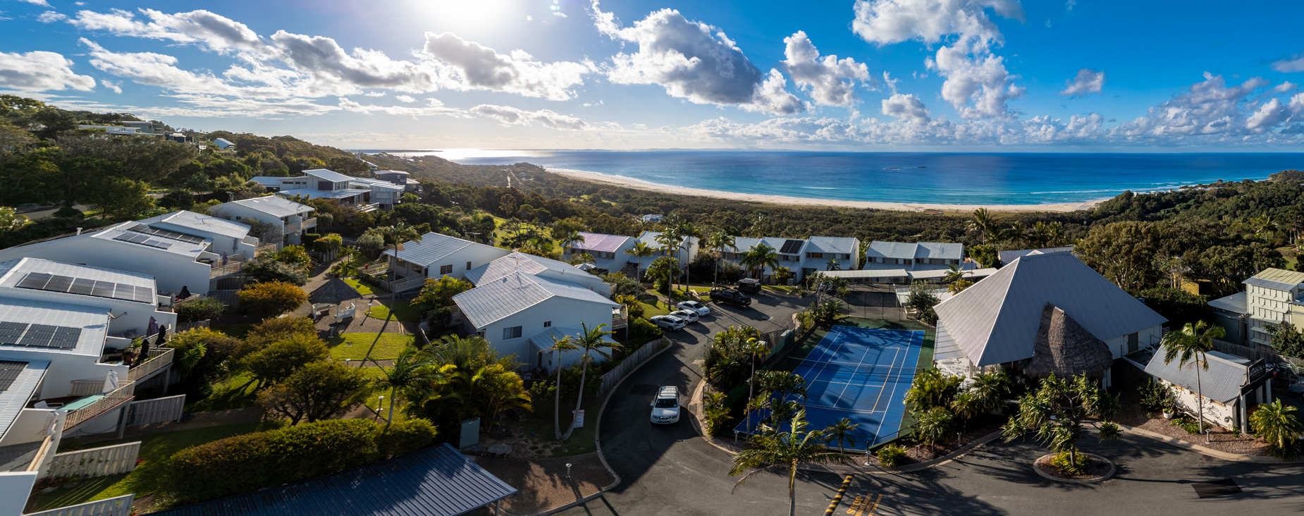 Pandanus Palms Resort from above, showing the tennis court, the villas and the beach beyond