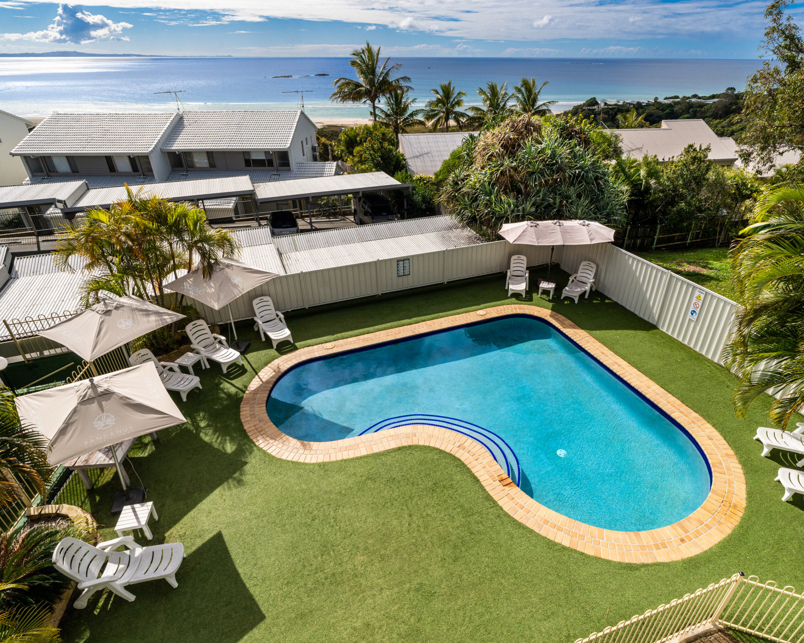 The swimming pool at Pandanus Palms Resort with the ocean beyond