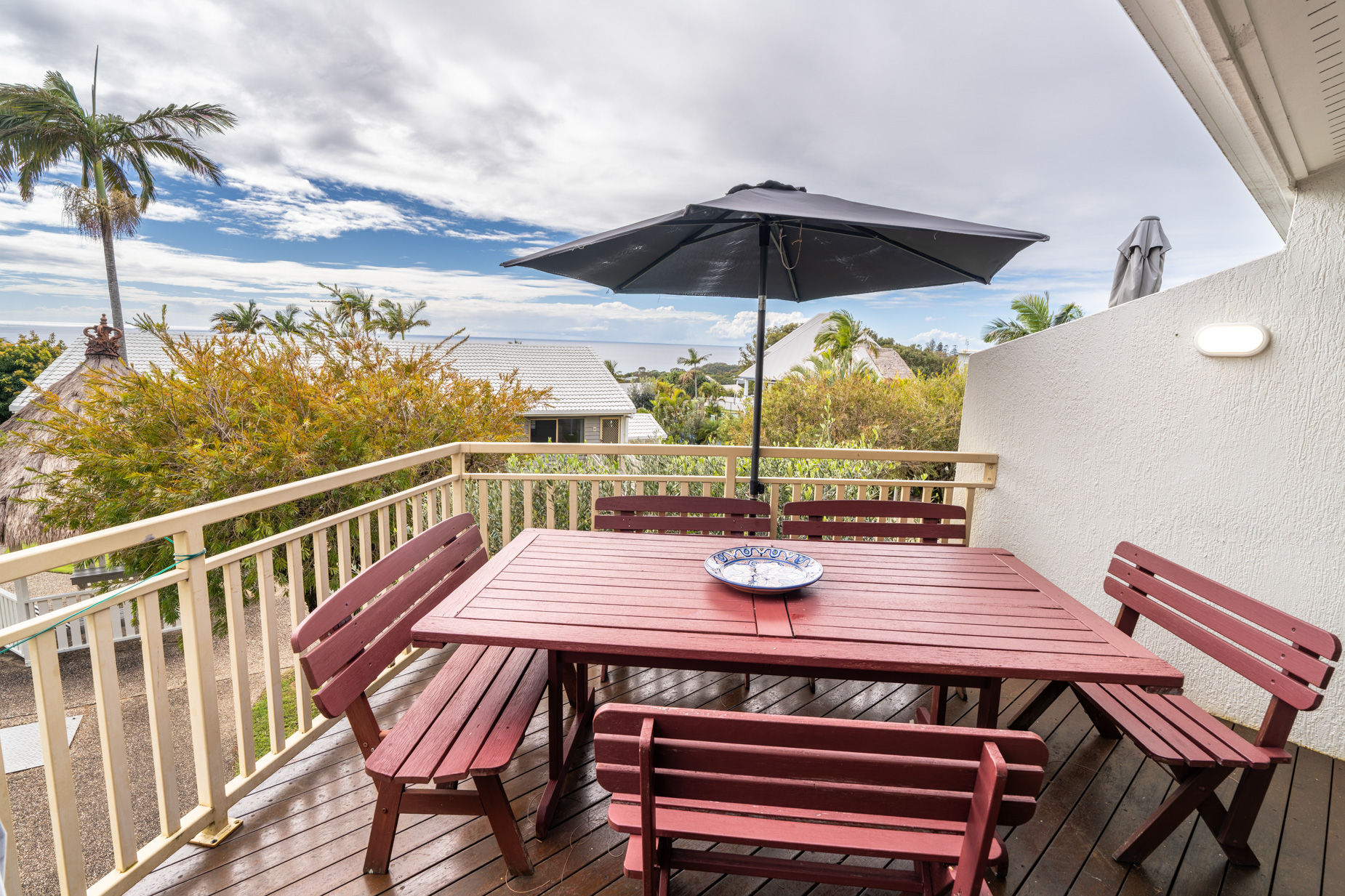 The private balcony of a Standard Ocean villa, with outdoor table and chairs among the palms