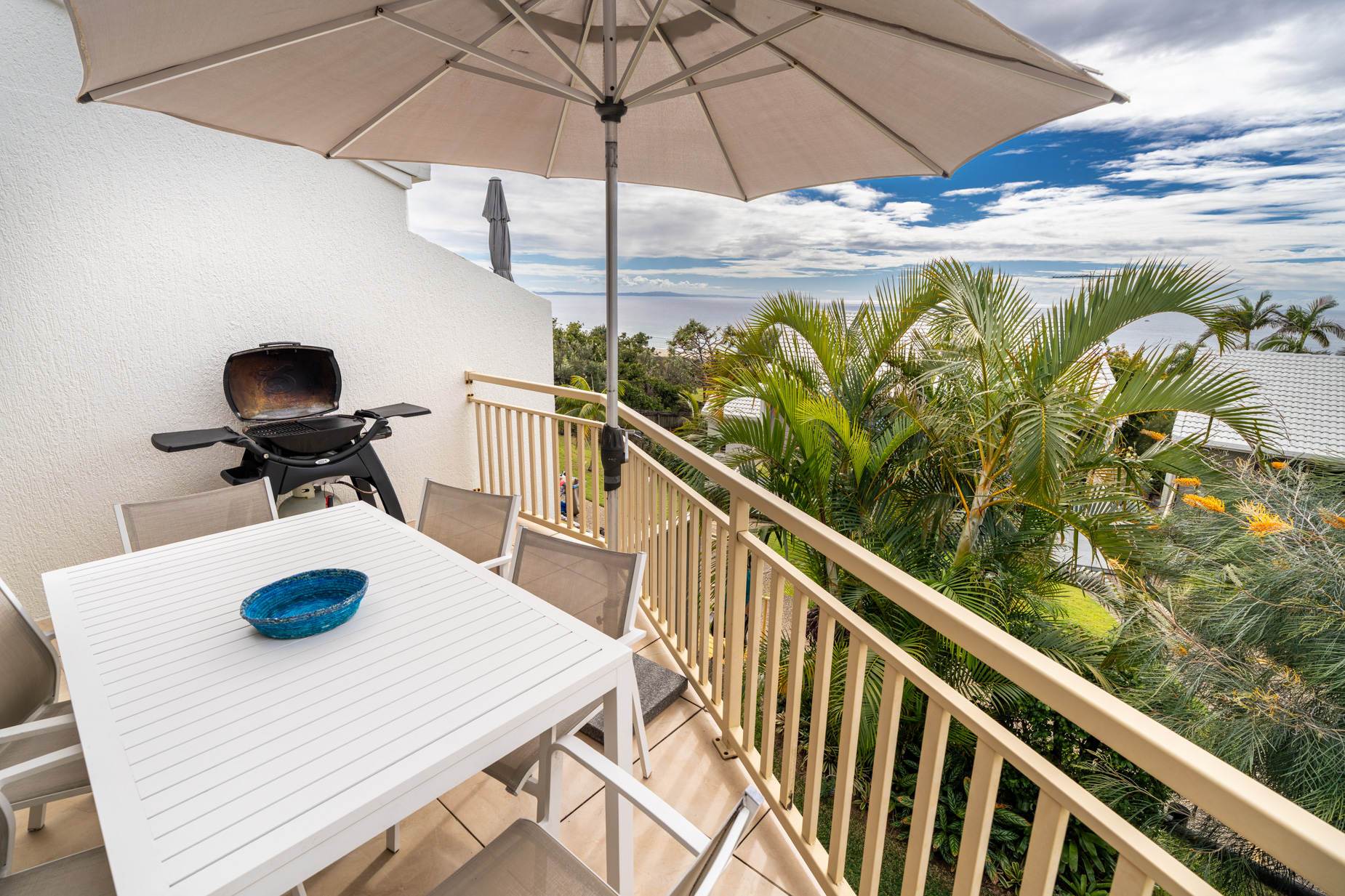 The private balcony of a Deluxe Ocean villa, with outdoor table and chairs among the palms