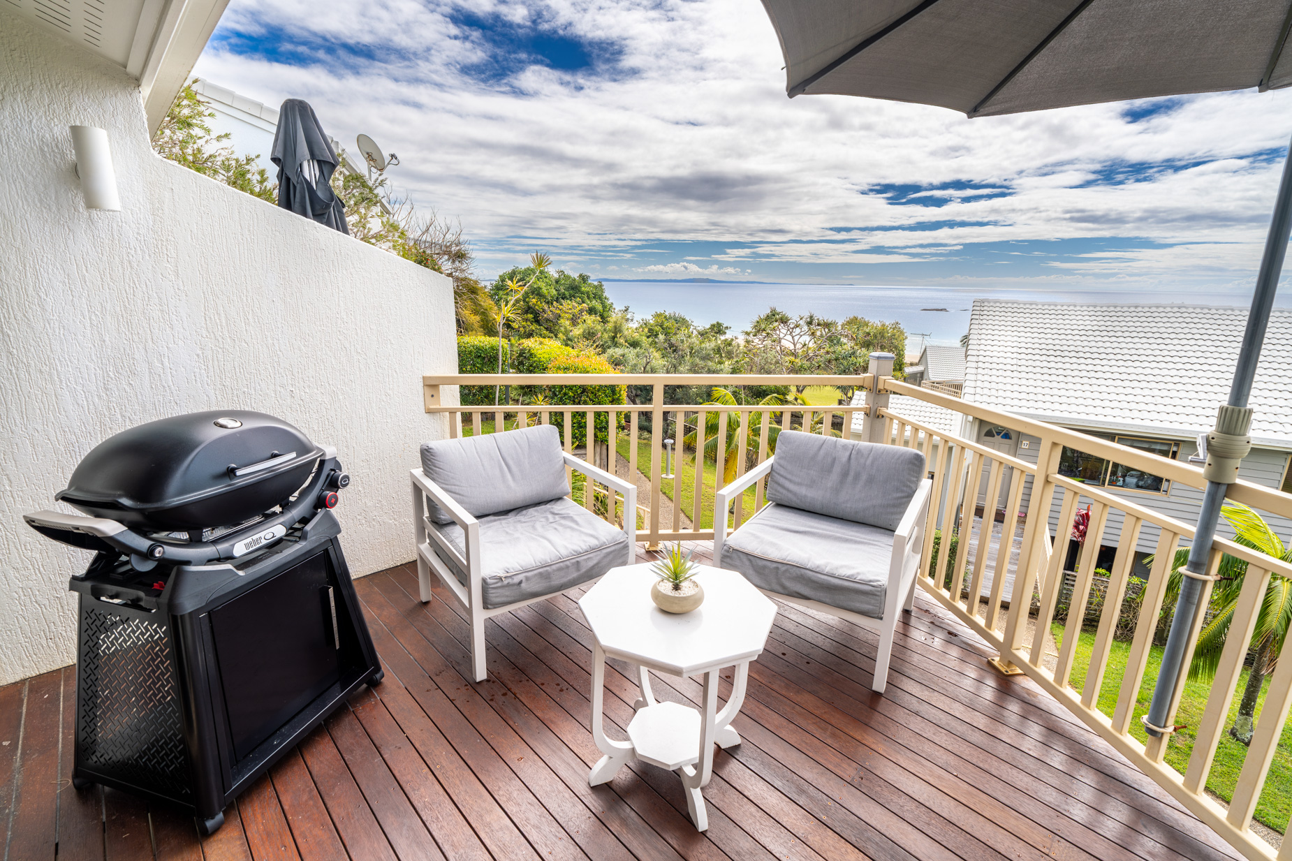 The private balcony of a Deluxe Ocean villa, with outdoor table and chairs among the palms