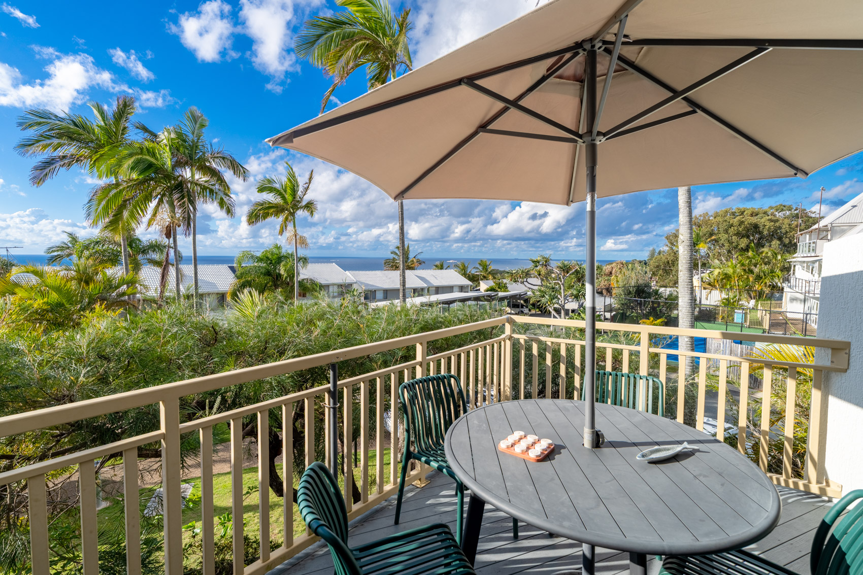 The private balcony of a Deluxe Ocean villa, with outdoor table and chairs among the palms