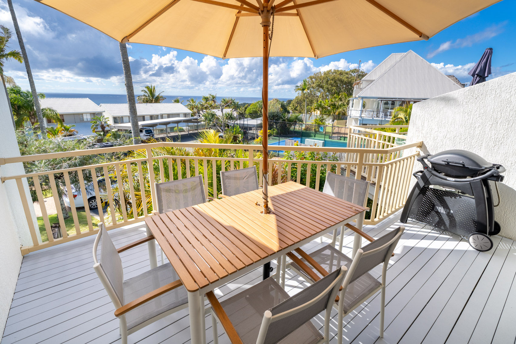 The private balcony of a Deluxe Ocean villa, with outdoor table and chairs among the palms