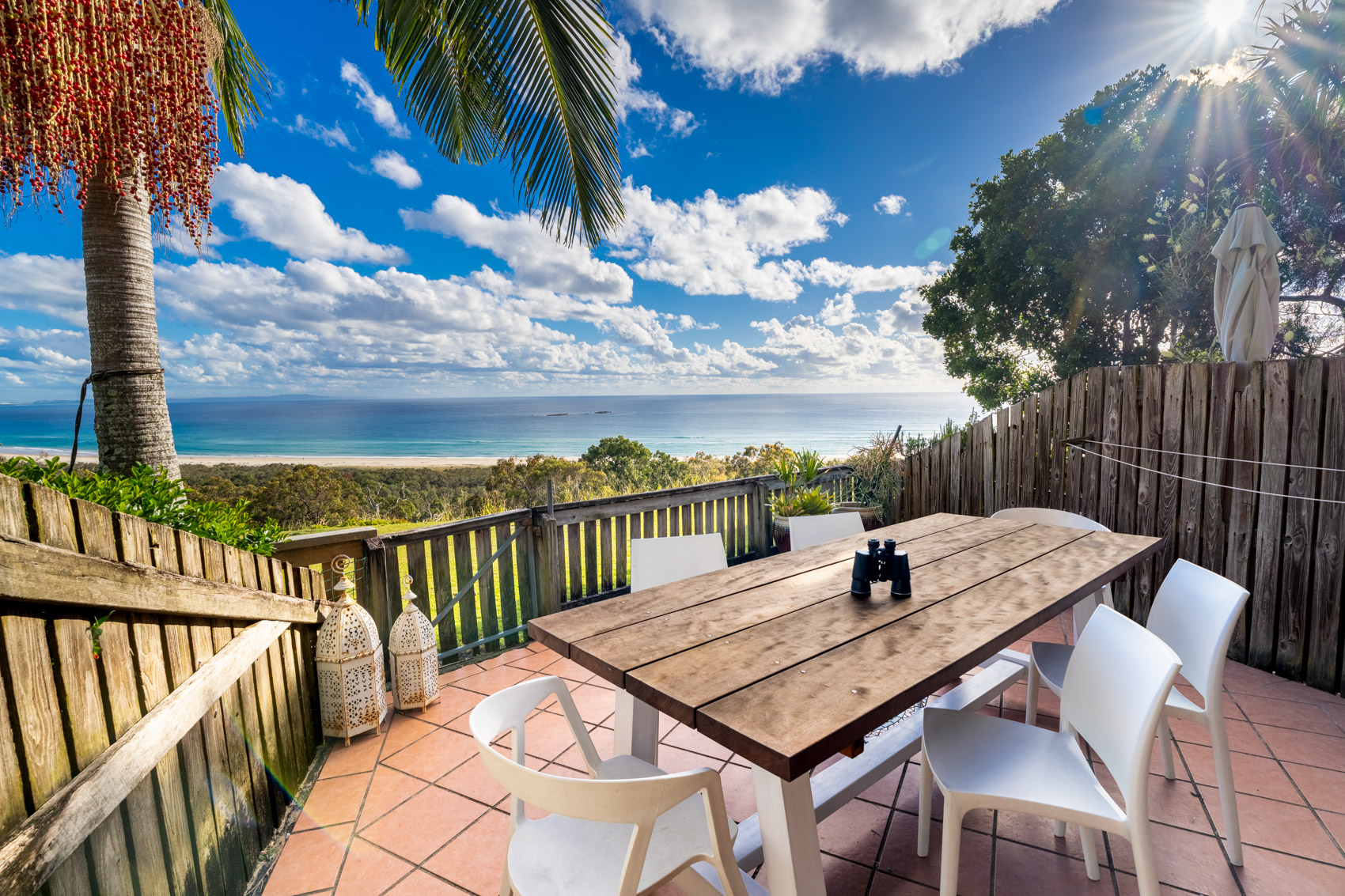 The private deck of a Prestige Headland Ocean villa, with outdoor dining looking over the headland to the sea