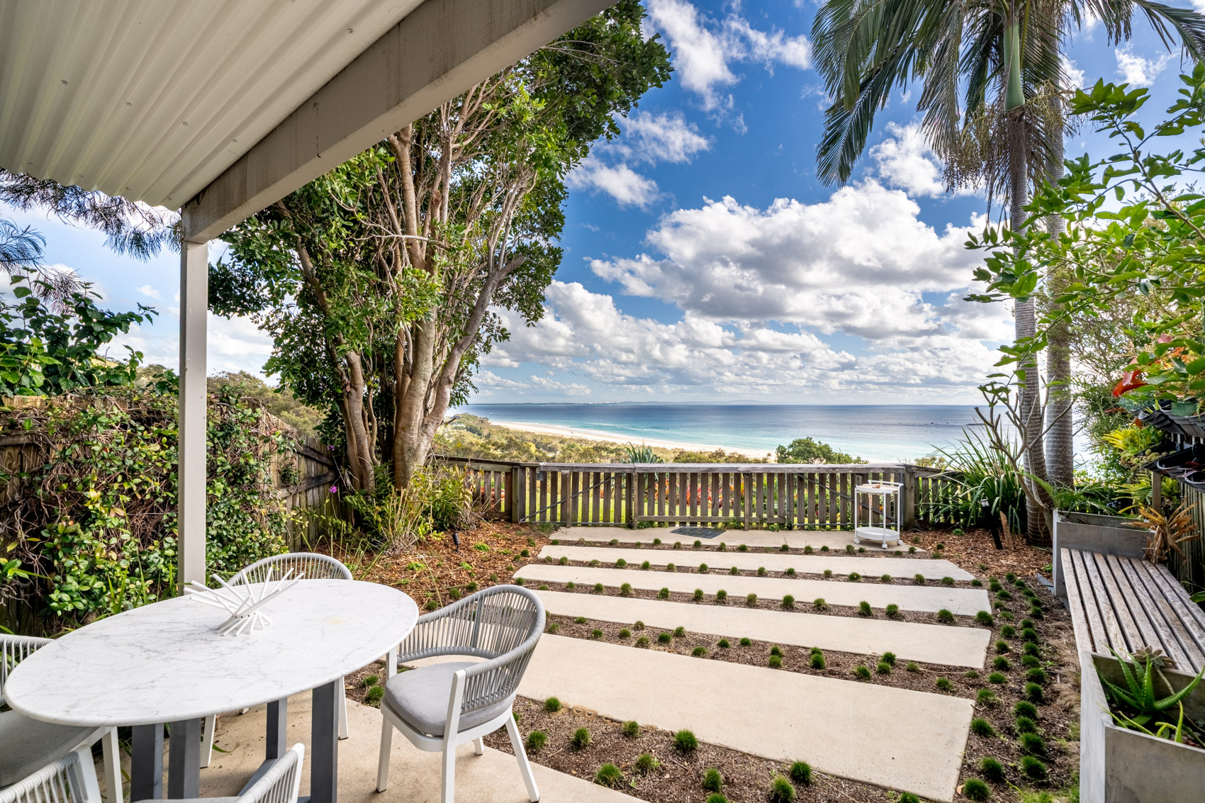 The covered patio of a Prestige Headland Ocean villa, looking across the garden to the sea