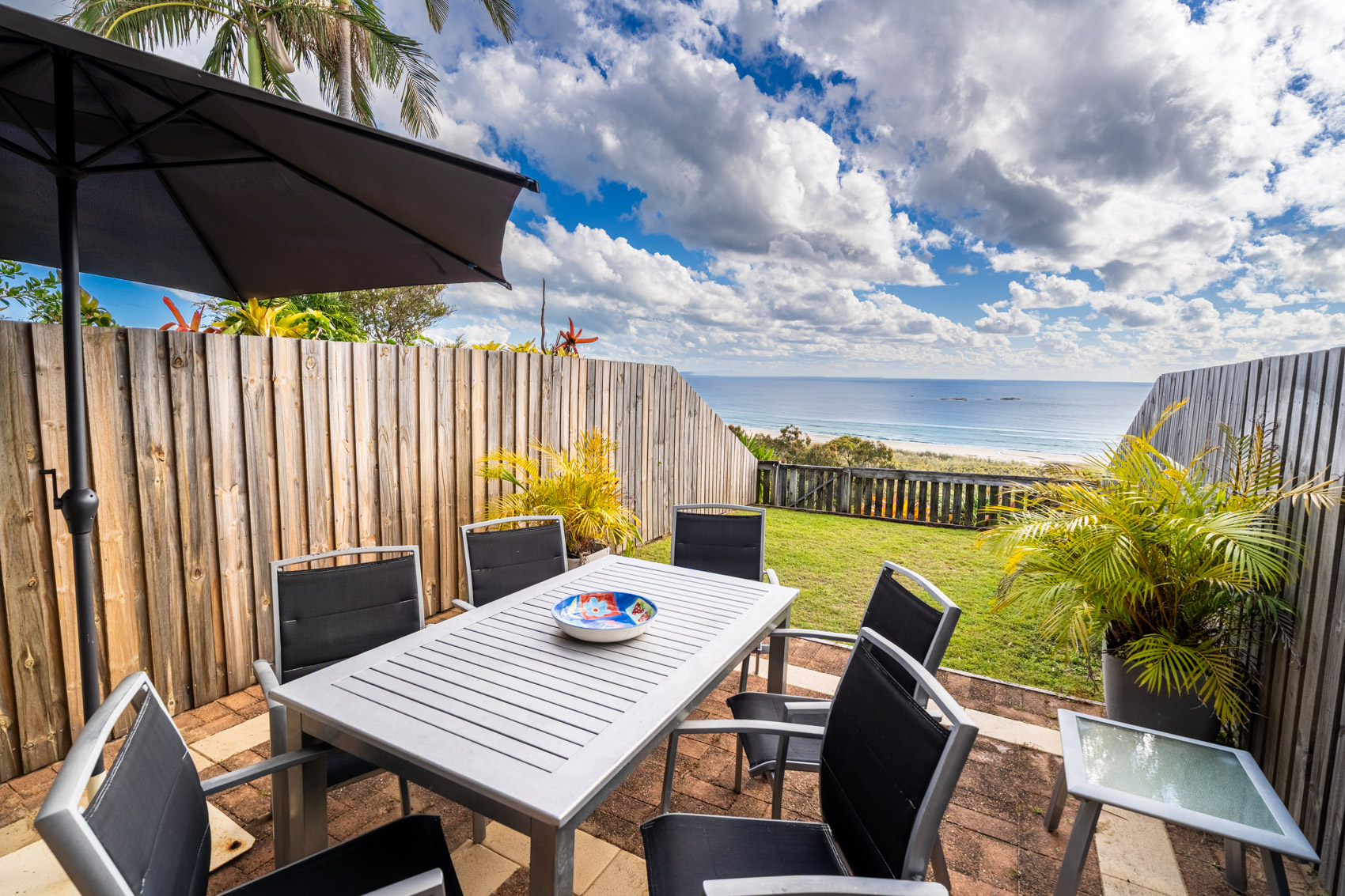 The private deck of a Premium Headland Ocean villa, with outdoor dining looking over the headland to the sea