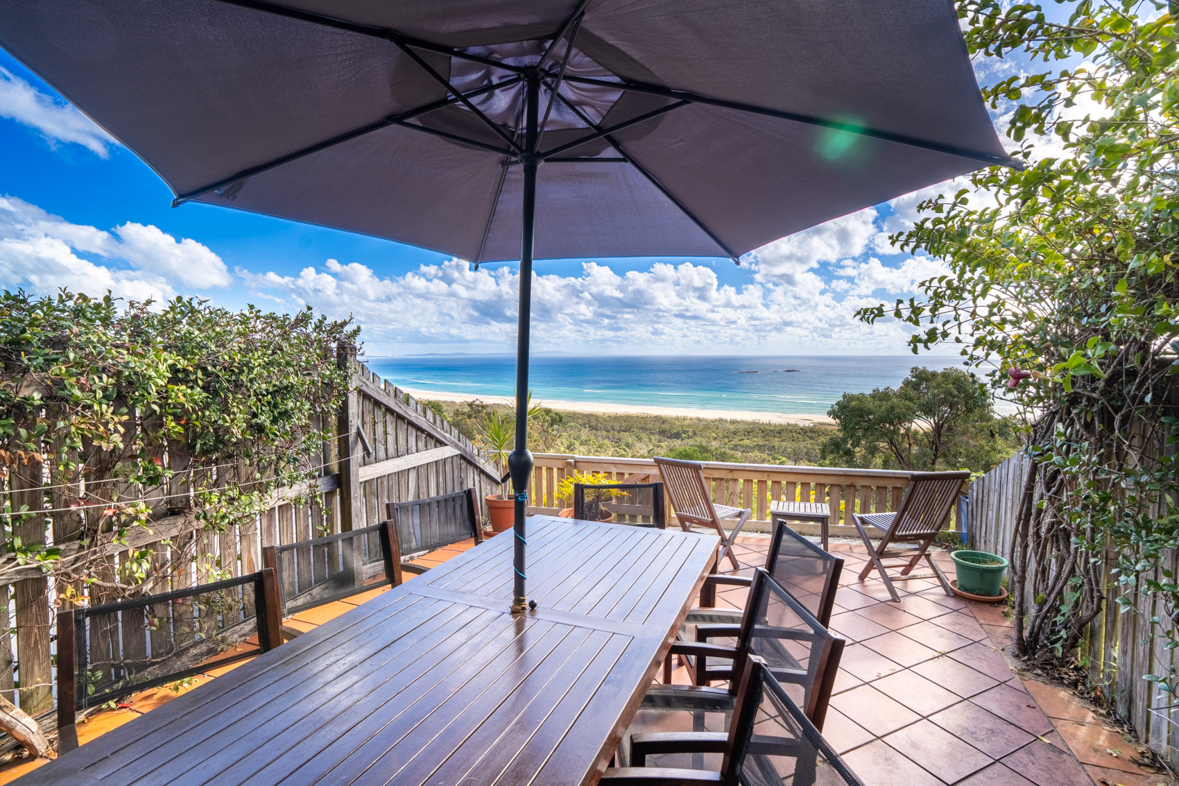 The private deck of a Premium Headland Ocean villa, with outdoor dining looking over the headland to the sea