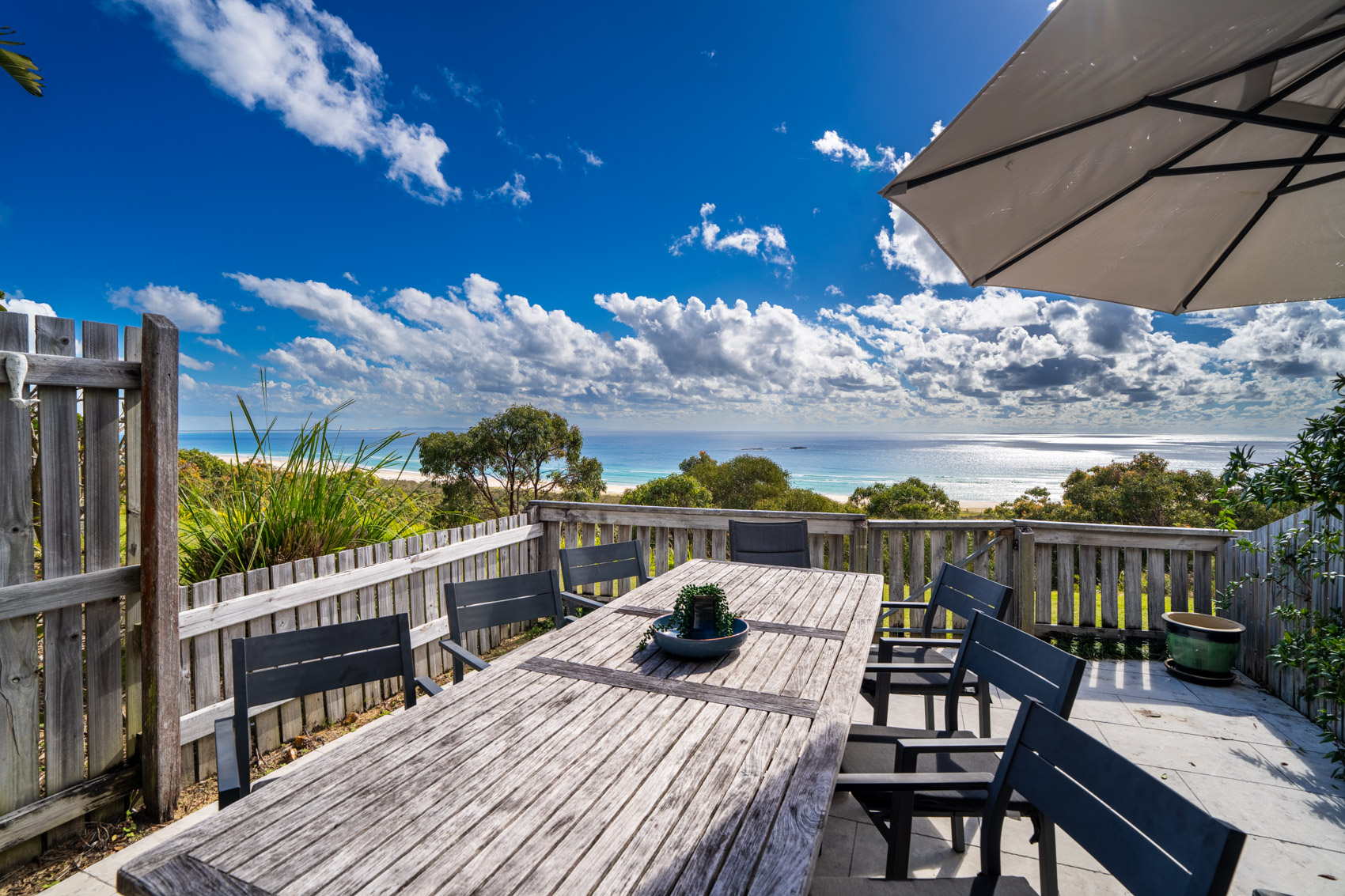 The private deck of a Premium Headland Ocean villa, with outdoor dining looking over the headland to the sea