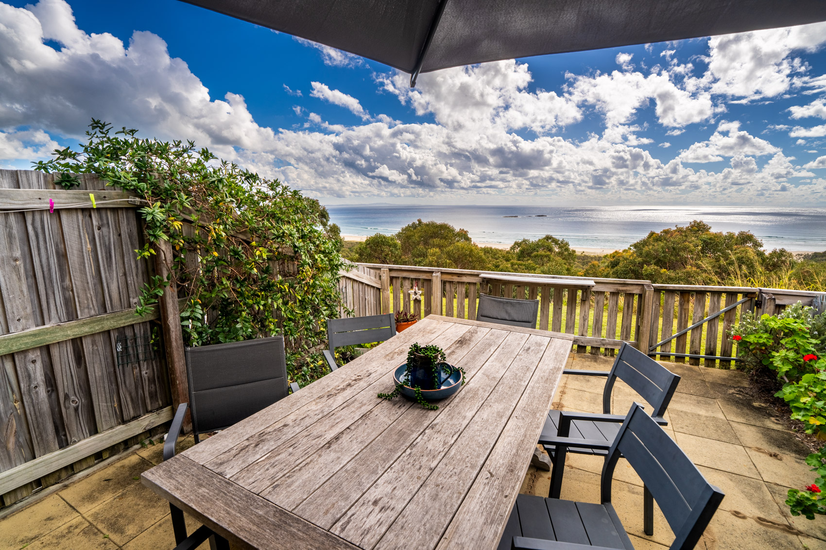 The private deck of a Premium Headland Ocean villa, with outdoor dining looking over the headland to the sea