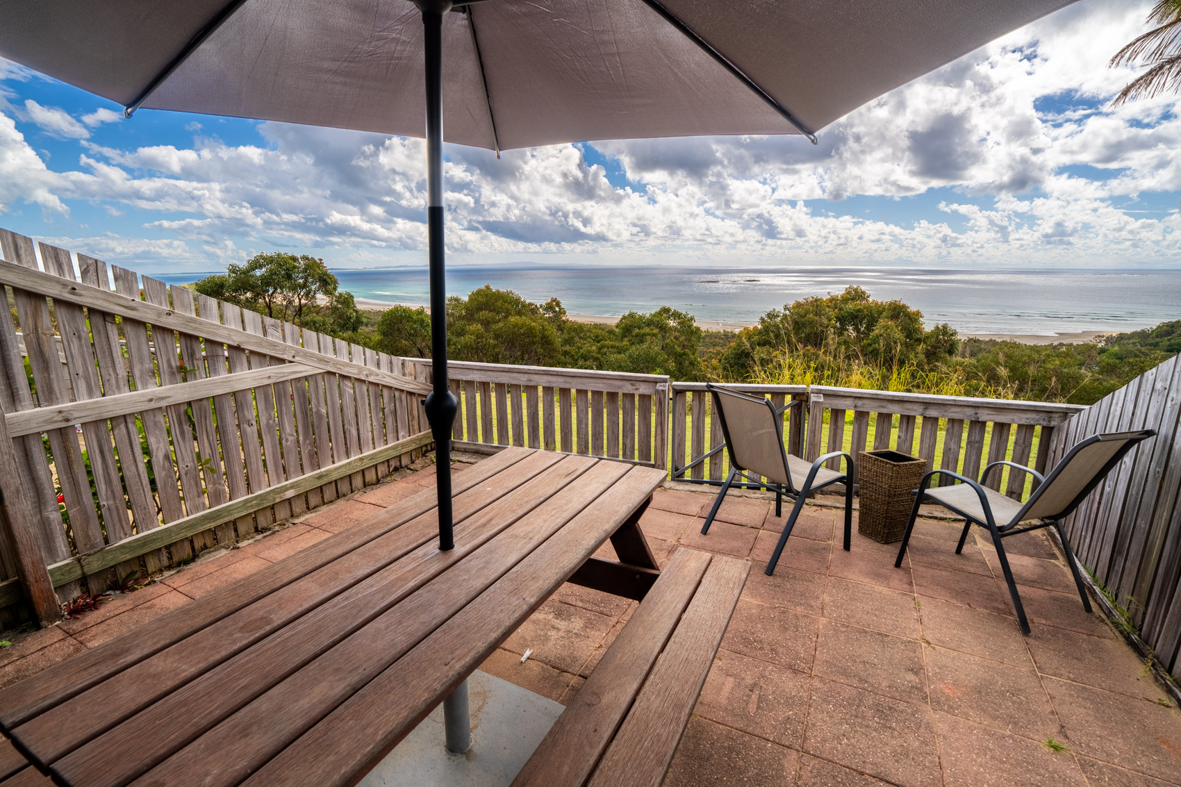 The private deck of a Premium Headland Ocean villa, with outdoor dining looking over the headland to the sea