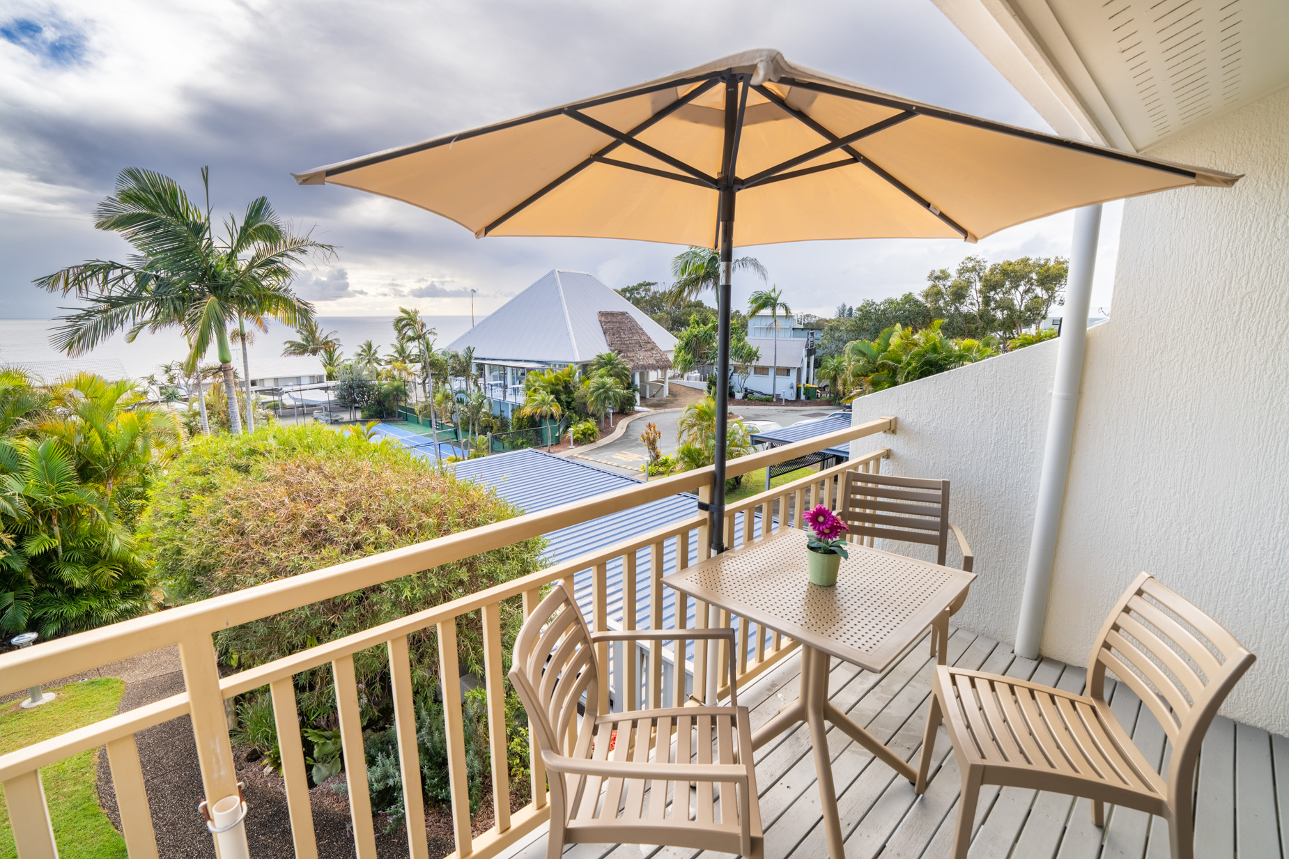 The private balcony of a Standard Ocean villa, with outdoor table and chairs among the palms