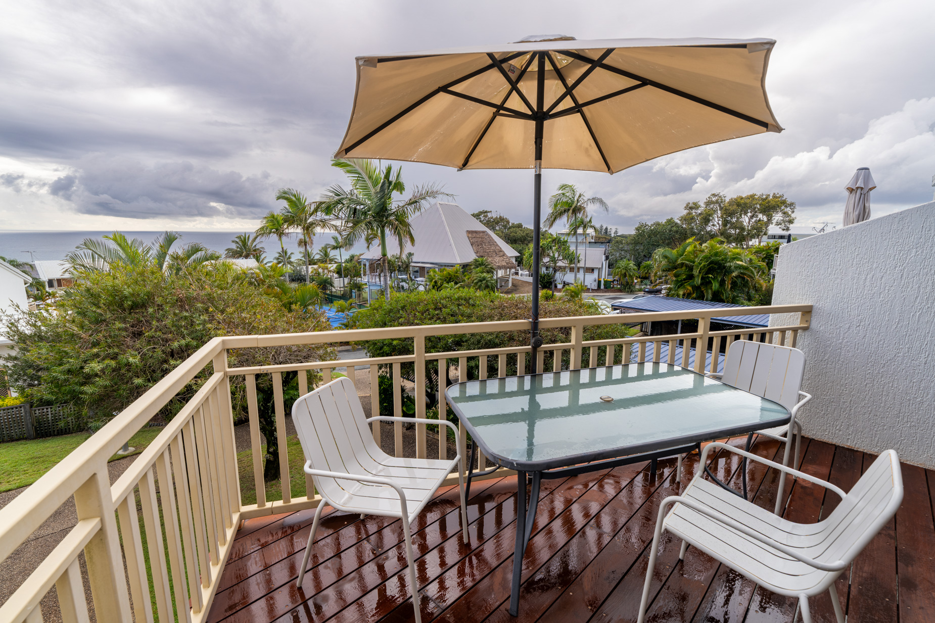 The private balcony of a Standard Ocean villa, with outdoor table and chairs among the palms