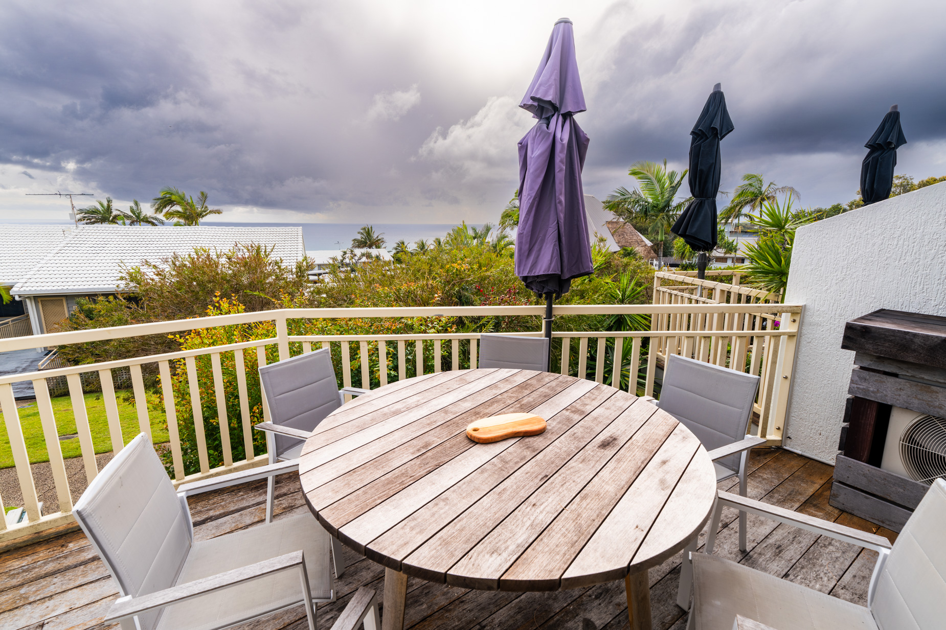 The private balcony of a Deluxe Ocean villa, with outdoor table and chairs among the palms