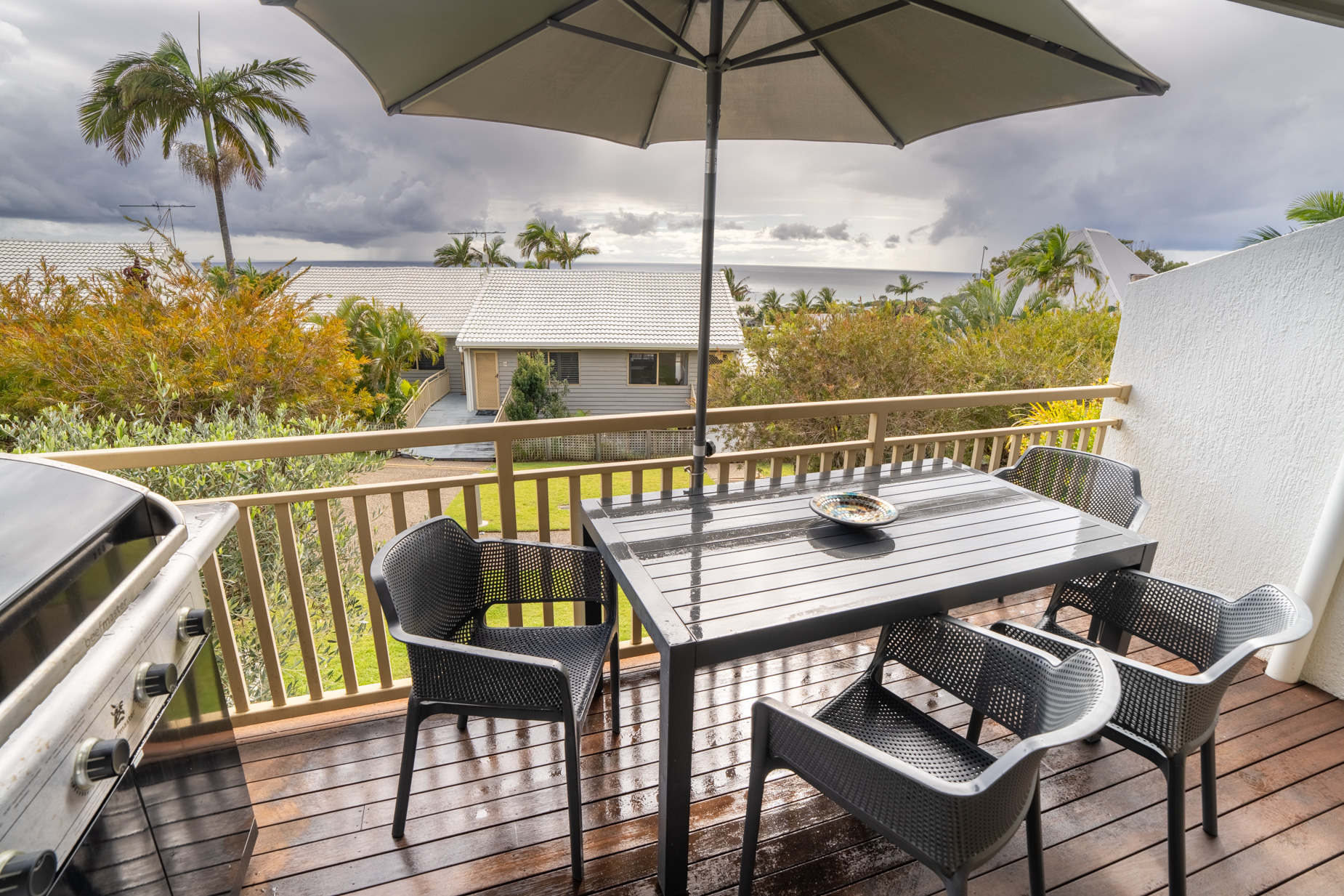 The private balcony of a Deluxe Ocean villa, with outdoor table and chairs among the palms