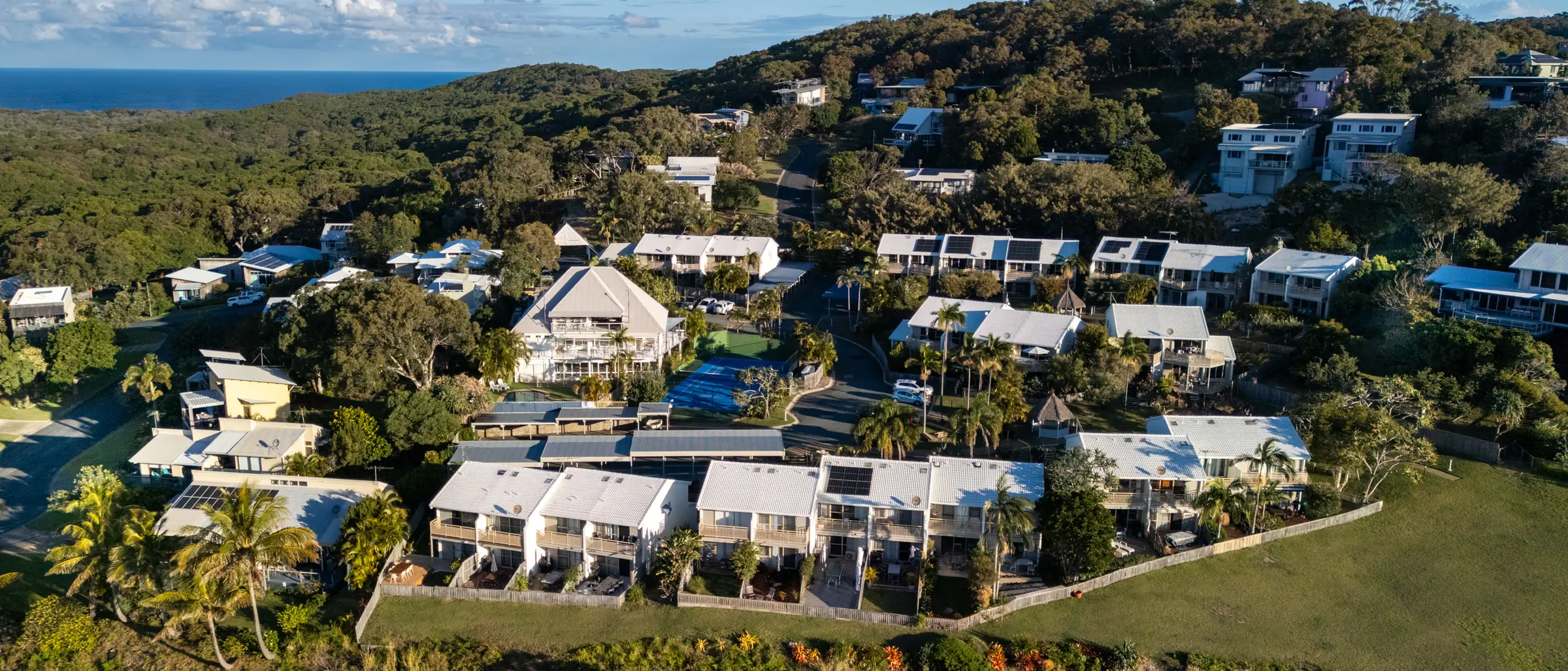 The headland reserve and coastal bushland beside Pandanus Palms Resort, seen from the air with the ocean on the horizon