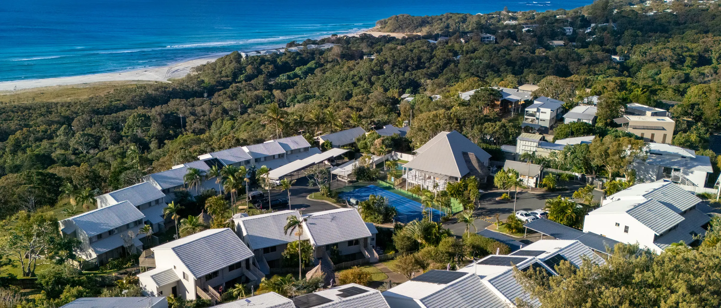 The headland at Pandanus Palms Resort from the air, with the villas among the trees and the beach and Coral Sea beyond