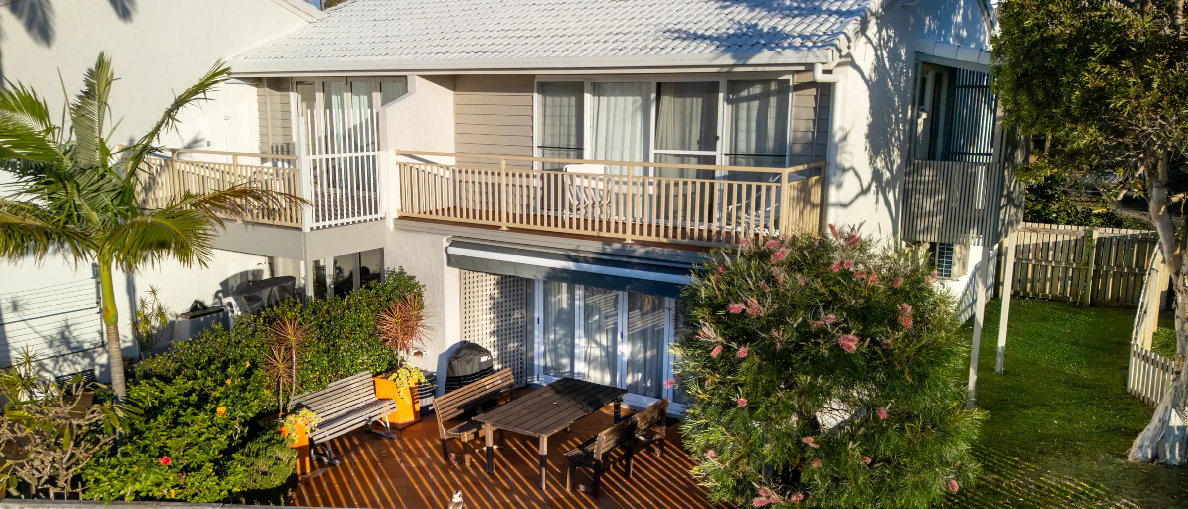 The edge of the headland reserve at Pandanus Palms Resort, with lawn and a white picket fence below the palms