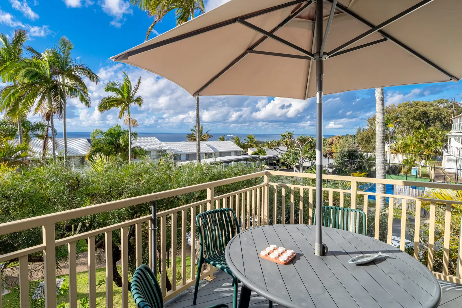 The private balcony of a Deluxe Ocean villa, with outdoor table and chairs among the palms