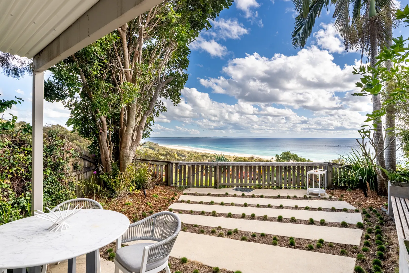 The covered patio of a Prestige Headland Ocean villa, looking across the garden to the ocean